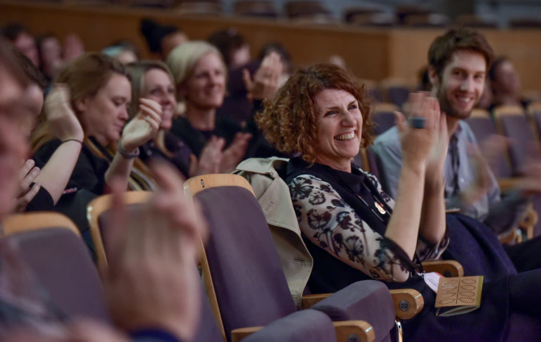 People clap and smile in a conference audience