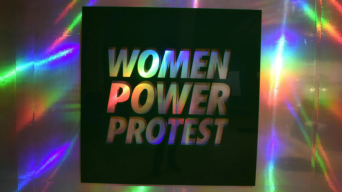 A holographic sheet reading Women Power Protest