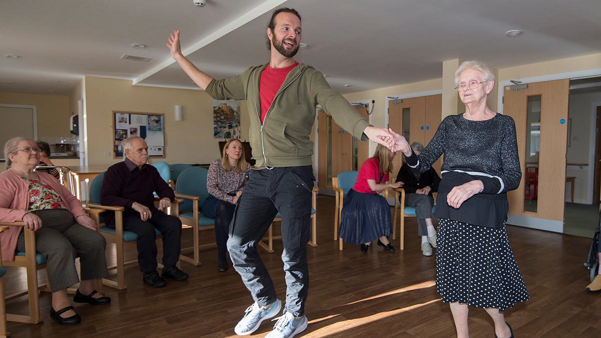 A man and an elderly woman dancing in a hall