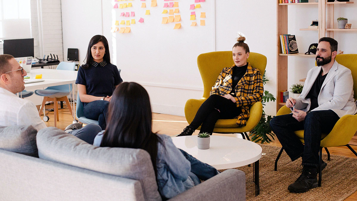 A group of colleagues sit around a table in a workplace