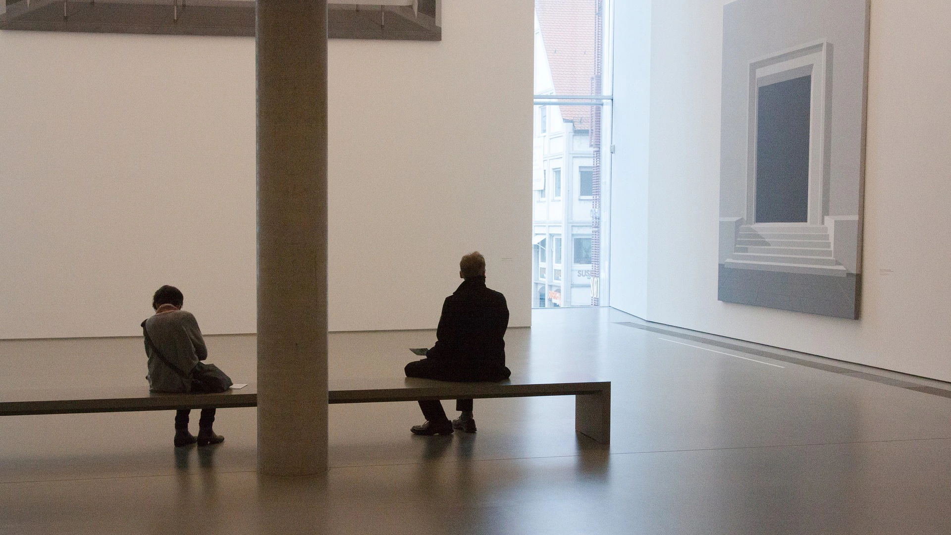 A person sits on a bench in a museum