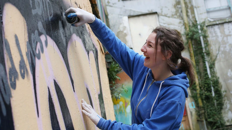 A young woman does graffiti art