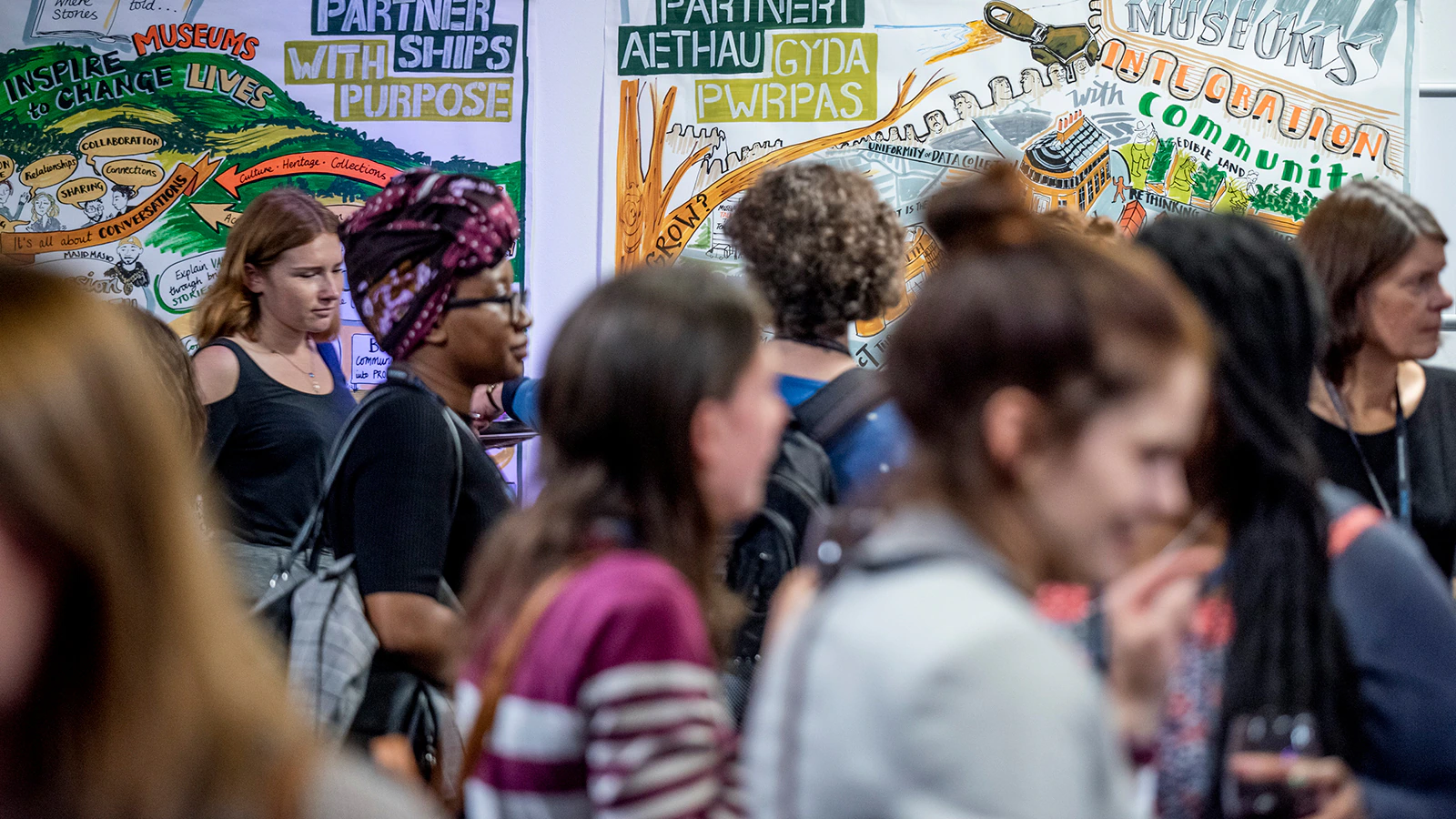 People walk in front of a colourful mural of wall art