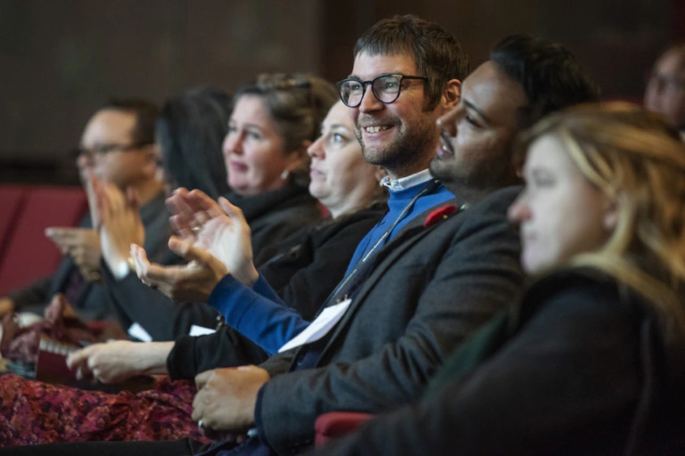 People sit and smile in a conference audience