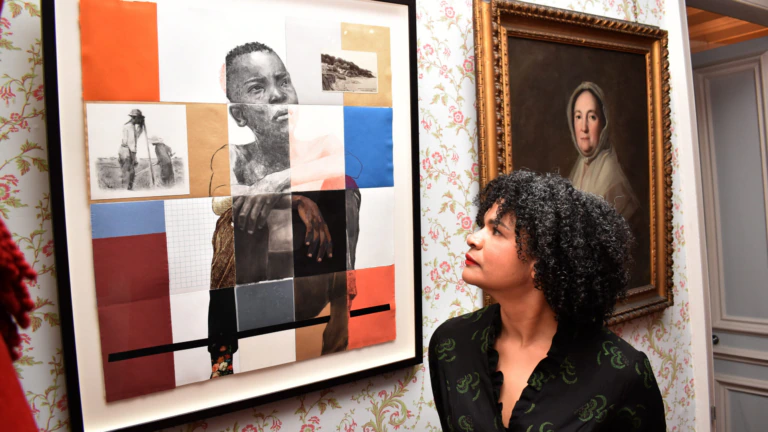 Artist Lela Harris stands with a portrait of a young Black man
