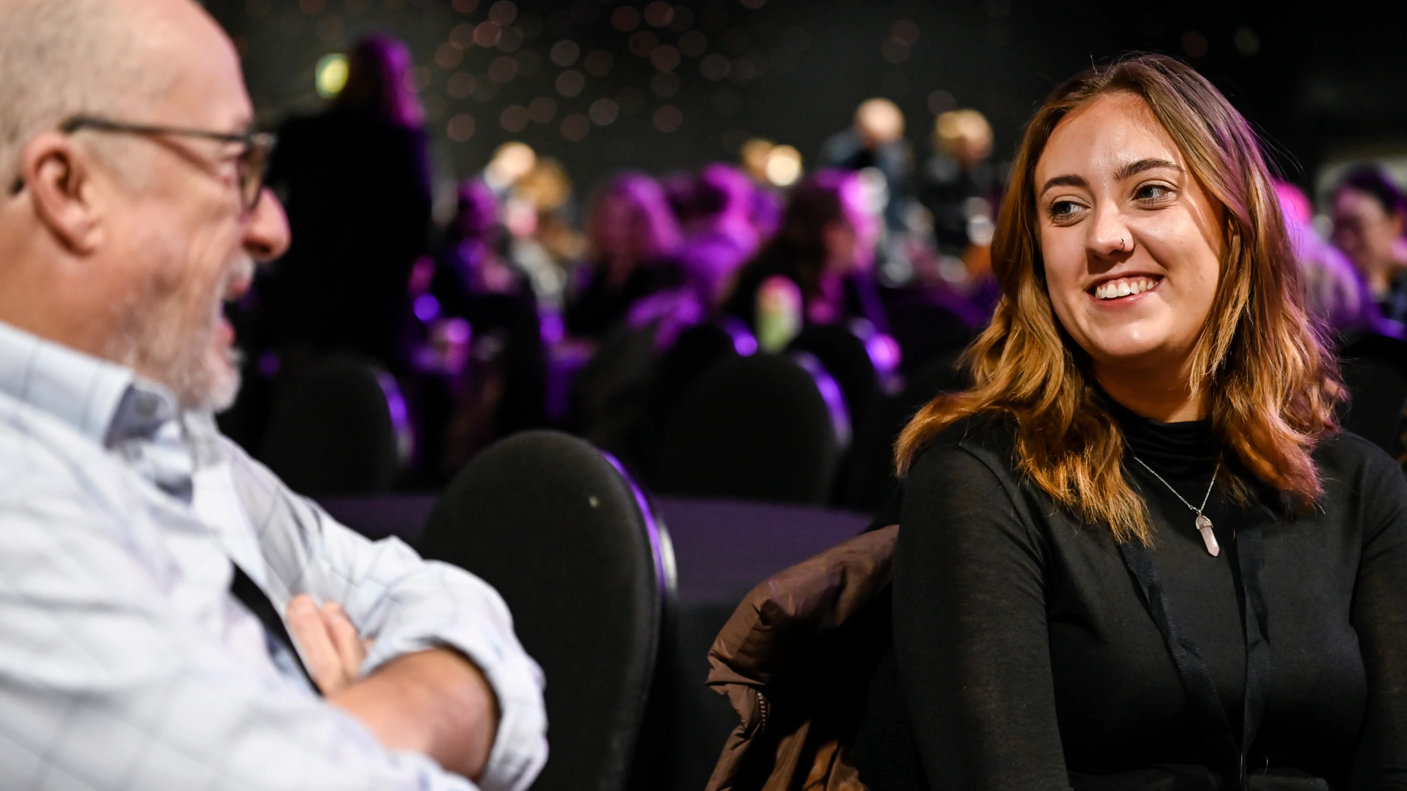 Two people sit and talk at an MA conference