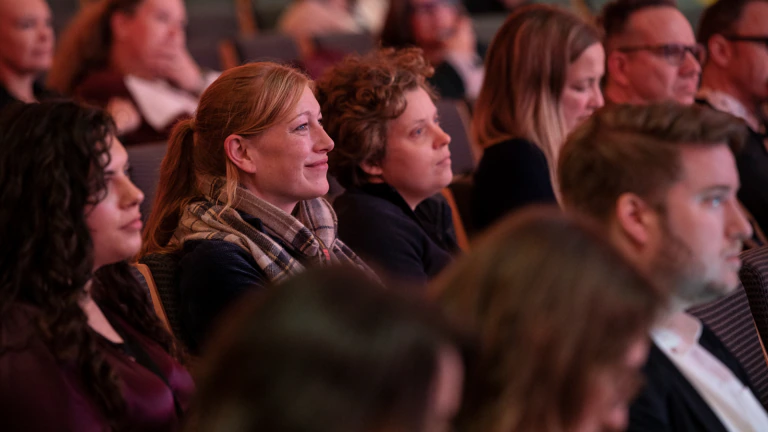 People sit in the audience of a conference session