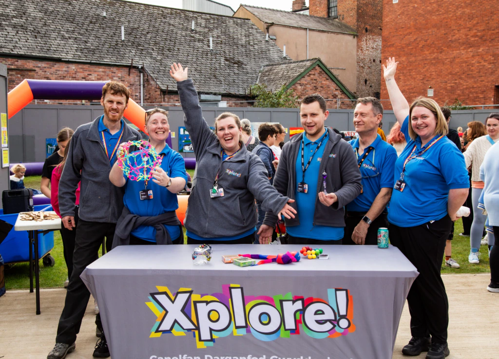 The Xplore team stands behind a table