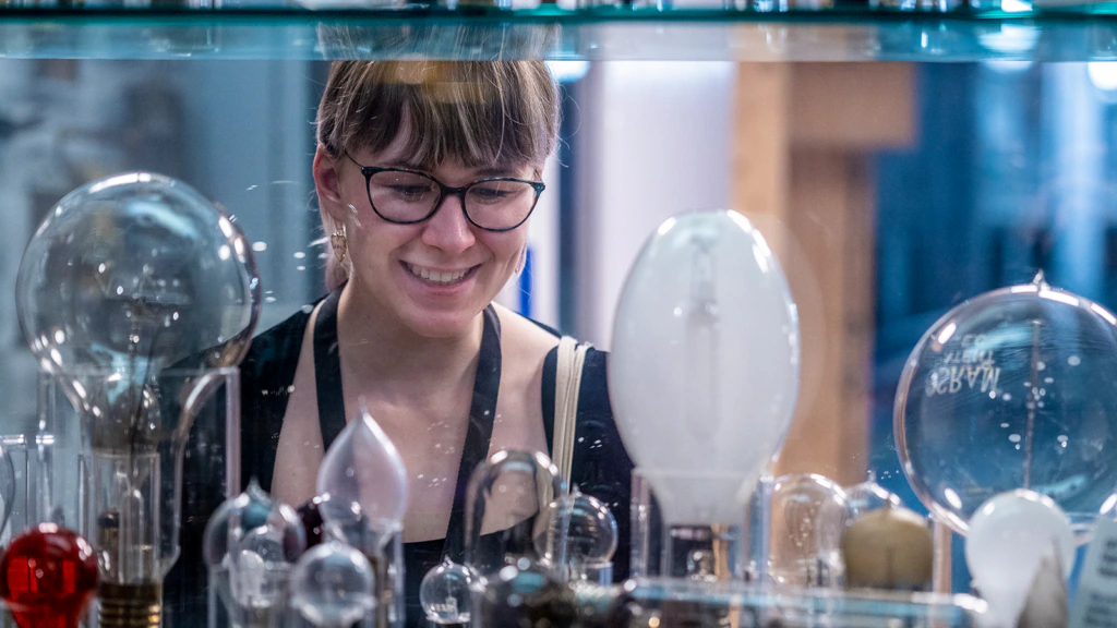 A person looks at blown glass objects in a cabinet