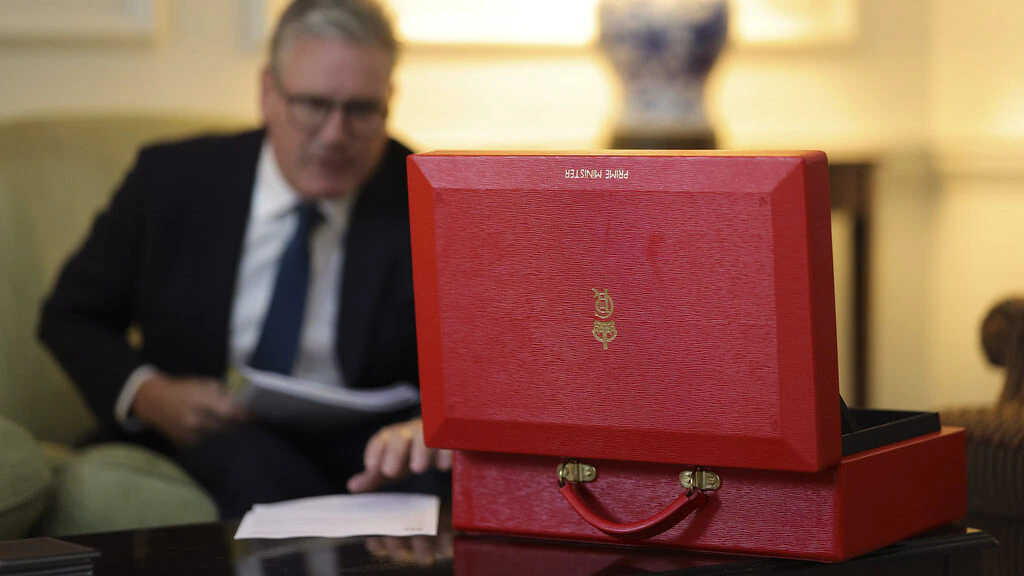 A red government briefcase in the foreground and prime minister Keir Starmer in the background