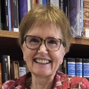 Marian Gwyn stands in front of a bookshelf