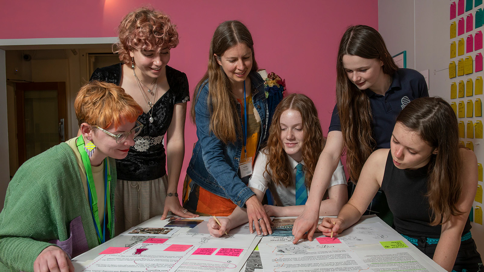Young people gather around a table to look at plans laid out
