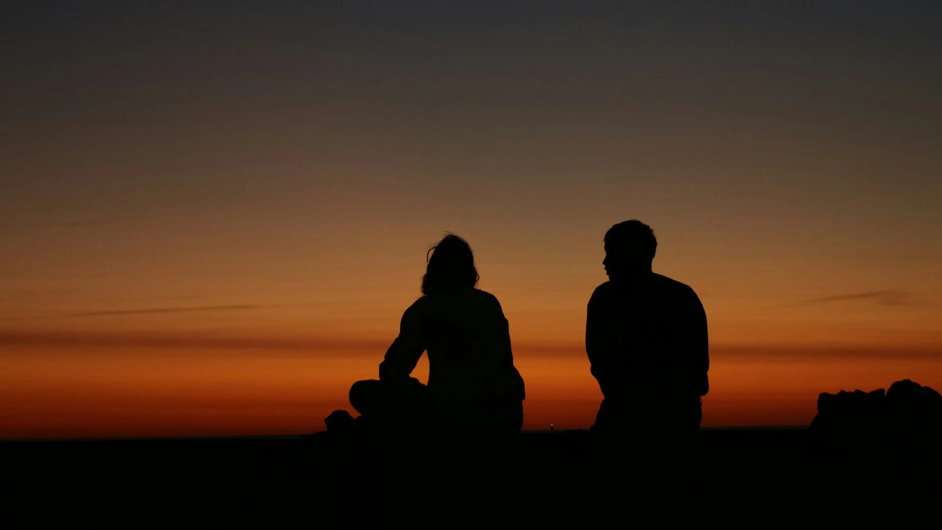 Two silhouettes sit and talk