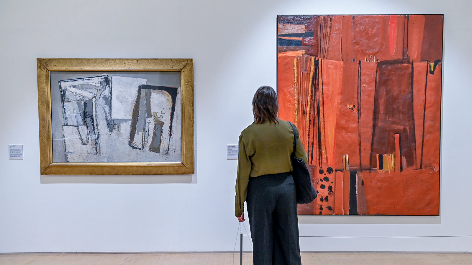 A person stands in a gallery, viewing two large abstract paintings