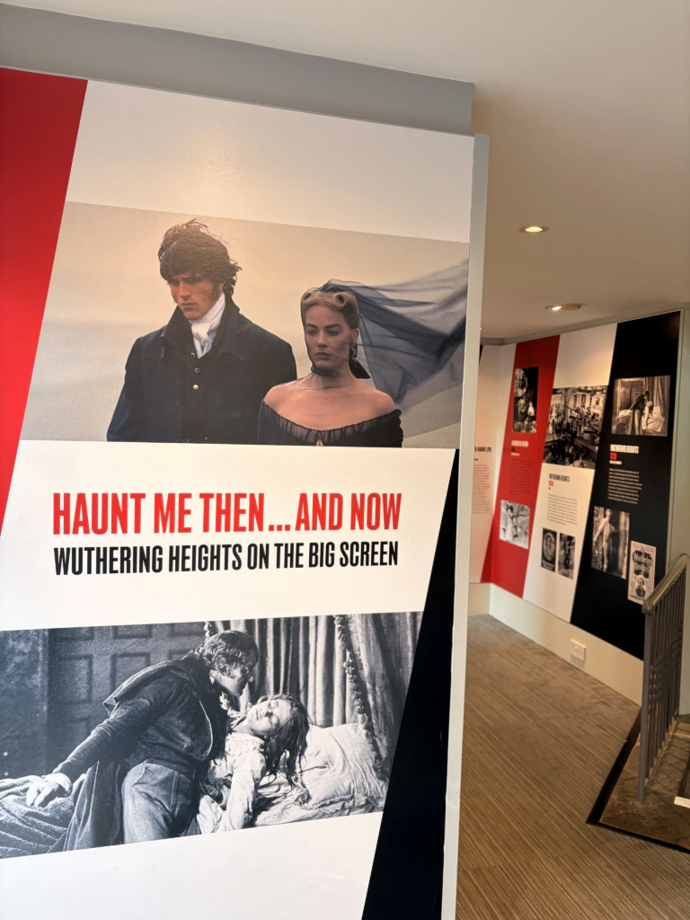 A display panel with images and text about Wuthering Heights adaptations. The top image shows a man and woman in period dress; the bottom image is a dramatic black-and-white film scene. Text reads: Haunt Me Then...And Now. Wuthering Heights on the big screen.
