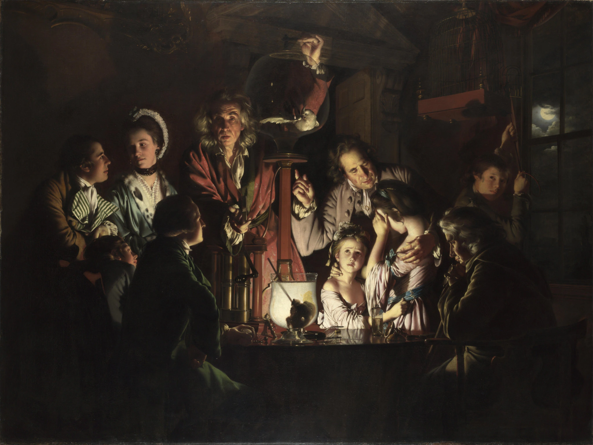 A group of seven adults and three children watch a man demonstrate a scientific experiment with a bird in a glass container, illuminated by candlelight in a dark, wood-paneled room at night.