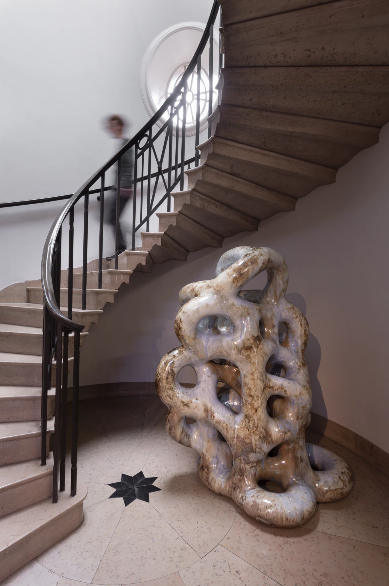 A sculpture at the bottom of a staircase as someone descends