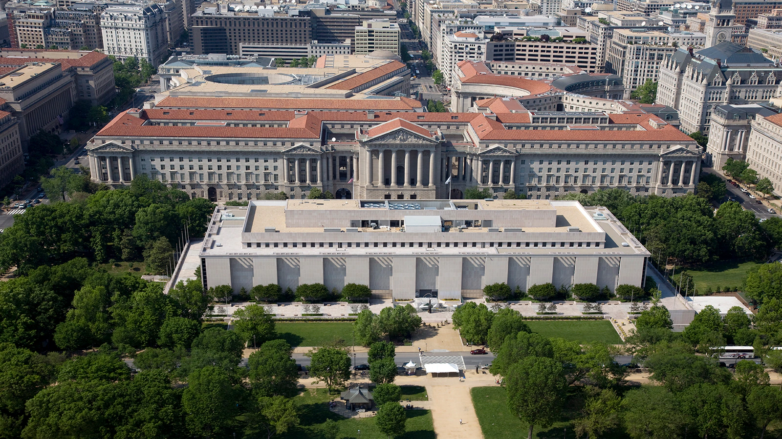 Aerial view of the National Museum of American History (foreground) and the Ronald Reagan Building and International Trade Center (background) in Washington, D.C., surrounded by trees and city buildings.