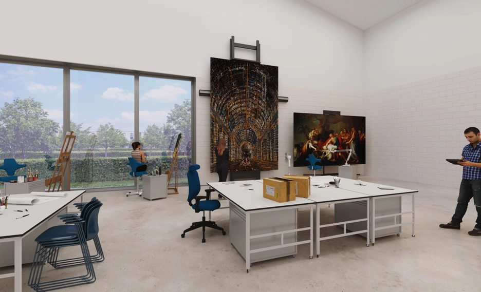 Art studio with easels, tables, and supplies. Two people work on paintings, one person stands near a large artwork, and another reads a tablet. Large windows show trees outside.