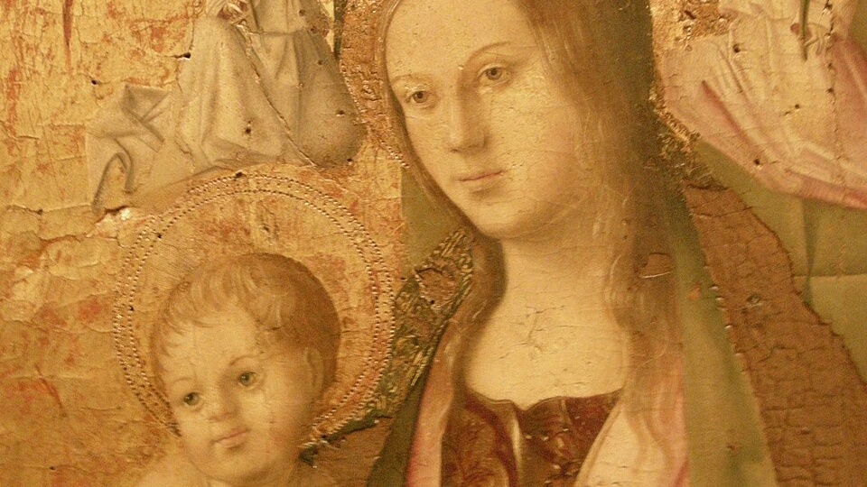 A close-up of a classical religious painting showing a woman with a halo holding a baby, with angels in the background. The painting is faded and has visible cracks.