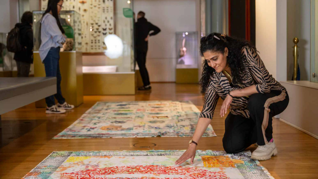 A woman looks at a tapestry on the floor at the Hunterian Museum