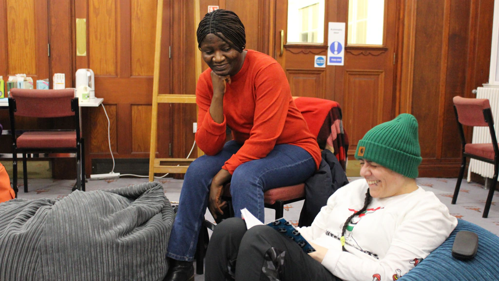 Two women sit together and chat while smiling