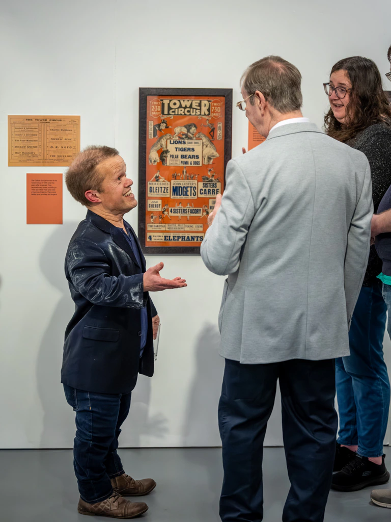 Three people stand and talk in a gallery space