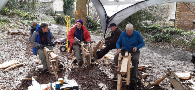 Men sit on camping chairs to discuss