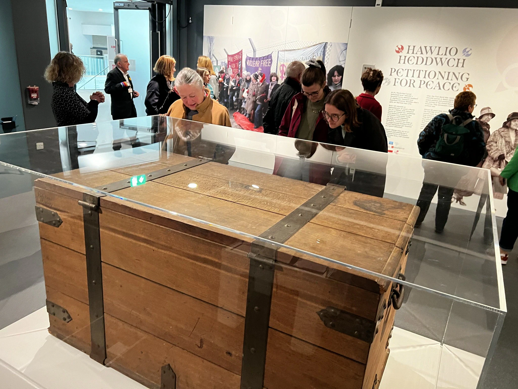 People viewing a large wooden chest at an exhibition at St Fagans